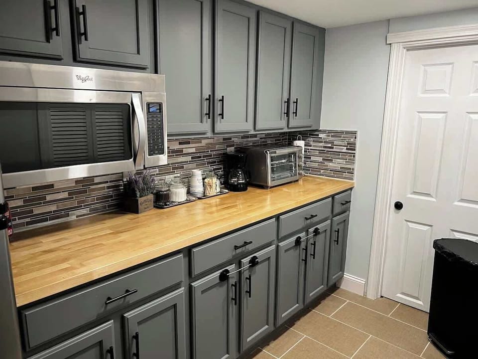 Half-kitchen with a microwave,  a large fridge, an air fryer/mini-oven, and a coffee maker. No conventional stove, kitchen sink or dishwasher.  