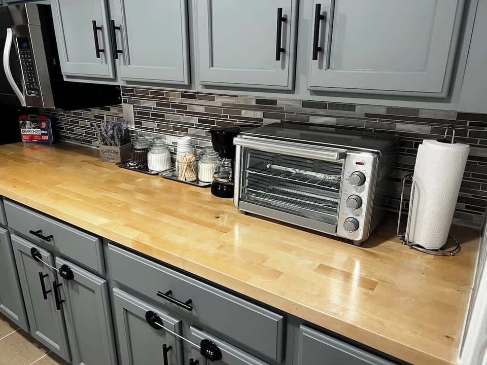 Half-kitchen with a microwave,  a large fridge, an air fryer/mini-oven, and a coffee maker. No conventional stove, kitchen sink or dishwasher.  