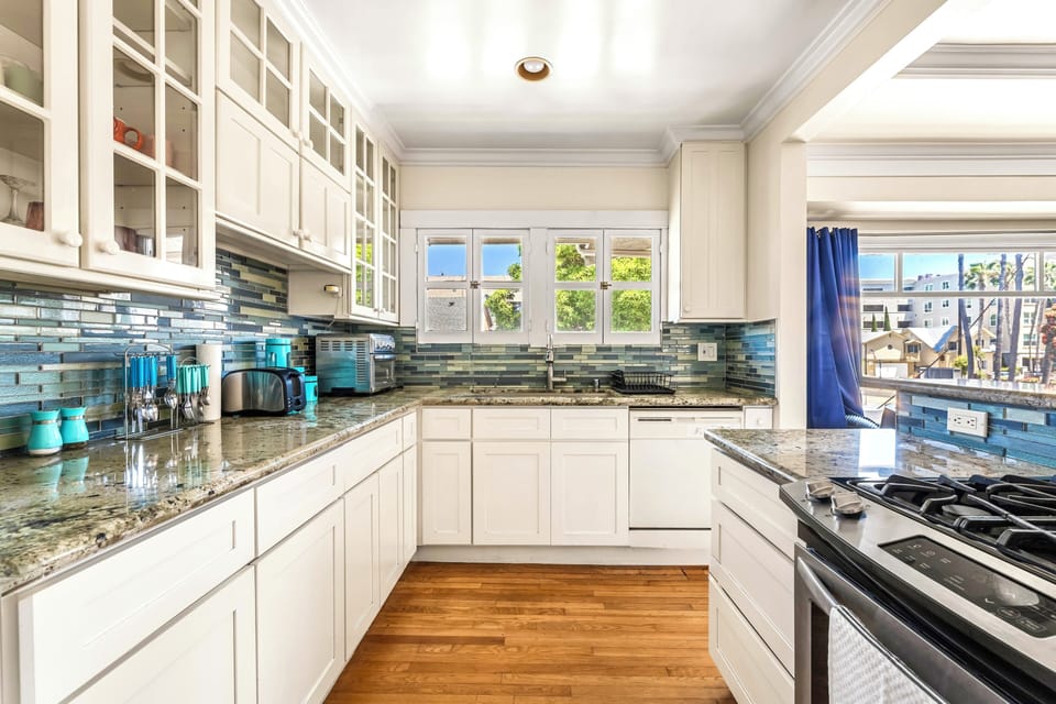 Bright coastal kitchen with gas range, granite tops, and coffee bar