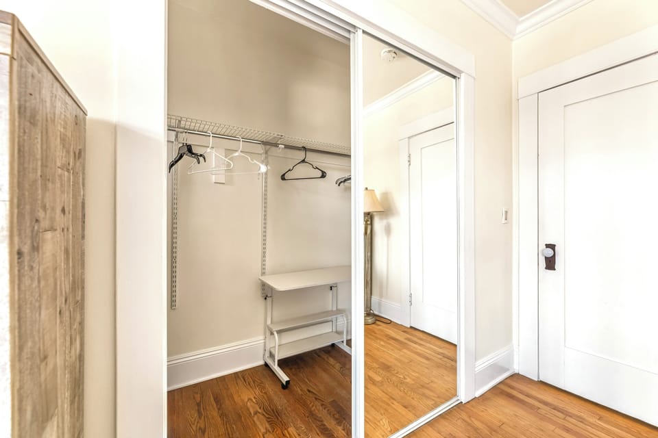Spacious mirrored closet with hangers and hardwood floors—perfect for unpacking.