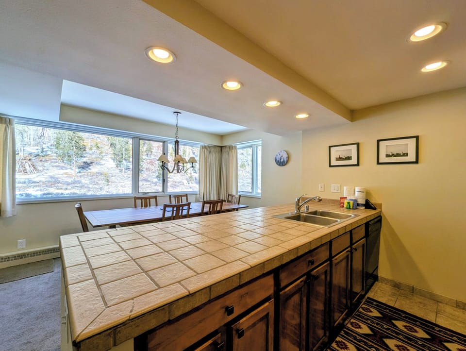 Your spacious kitchen and dining area features tile countertops, warm wood cabinetry, and large windows overlooking scenic desert landscapes.