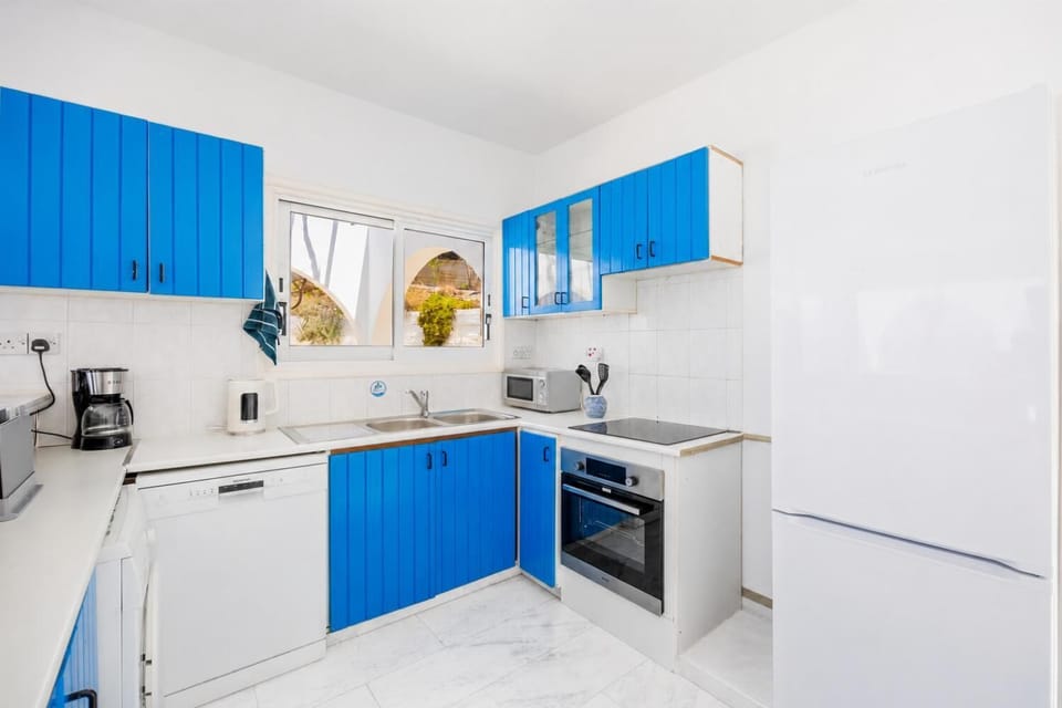 Bright kitchen with vibrant blue cabinetry, modern appliances, and a clean Mediterranean style.