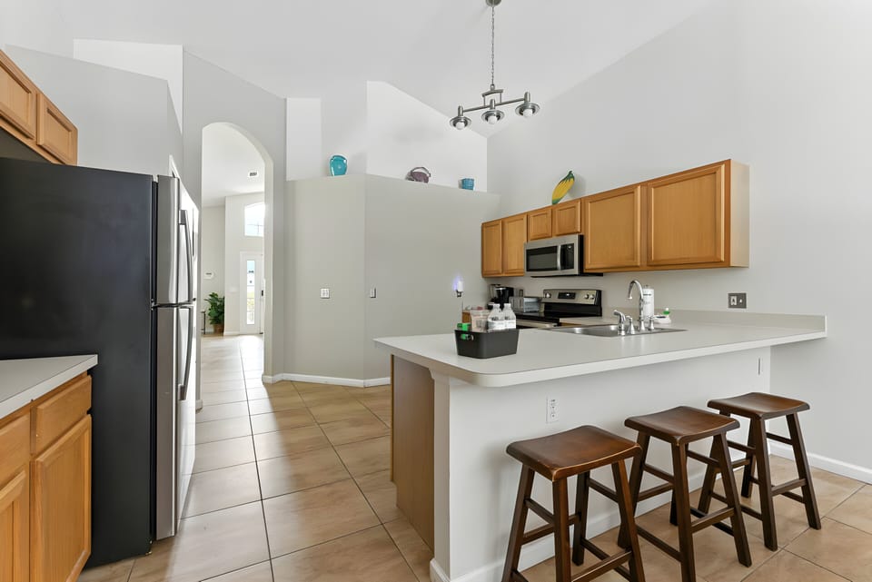 Welcome to a bright kitchen with warm wooden cabinets and sleek countertops, perfect for casual breakfasts at the bar with charming stools.