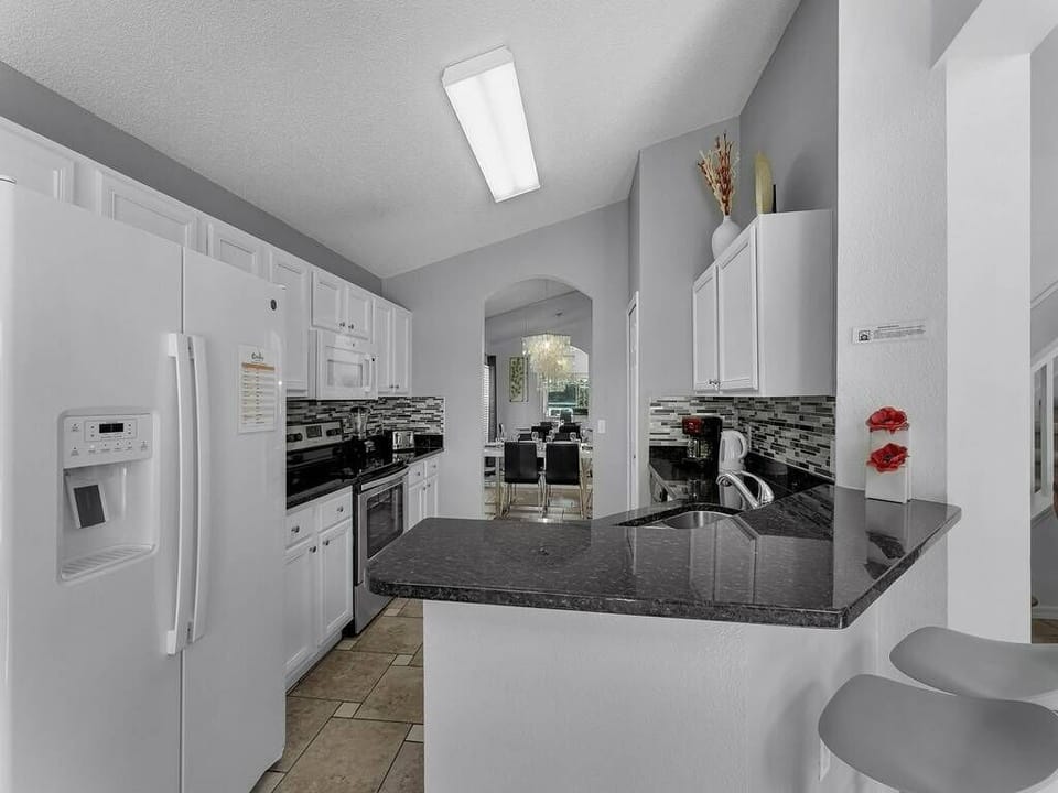Experience a bright kitchen with sleek white cabinets and bold black granite countertops, ideal for your cooking adventures. The open layout invites natural light, and cozy bar stools provide a welcoming spot for casual dining.