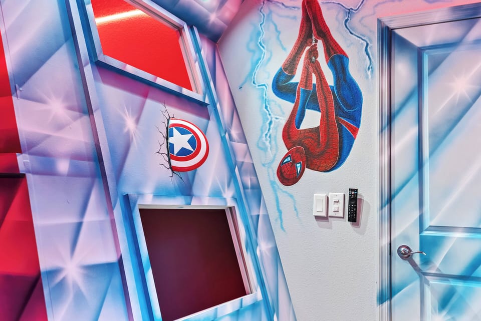 Enter a lively room adorned with vibrant murals, including a playful Spider-Man design that inspires imagination. The bright red and blue accents create a whimsical atmosphere, ideal for kids and those young at heart.
