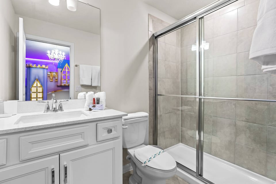Bright and functional, this bathroom features a sleek glass shower and a classic white vanity that offers ample space for your essentials. Enjoy the comforting ambiance created by the soft overhead lighting and elegant finishes.