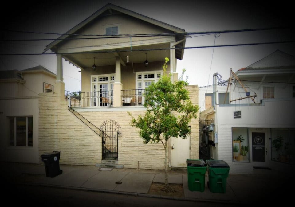 Exterior of building on Magazine Street.  Stairs lead up to porch and entrance to apartment.