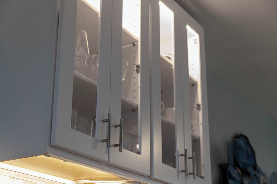 Stylish glass-front kitchen cabinets with soft lighting and organized storage