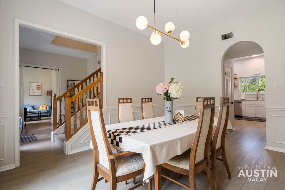 Dining table, center stage. Flowers fluffed, runner crisp, kitchen clinks cue the next scene.