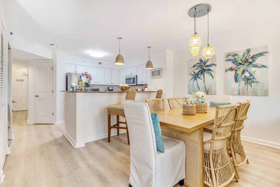Gather around your spacious dining table with coastal charm, where woven chairs and tropical artwork create the perfect setting for memorable meals.