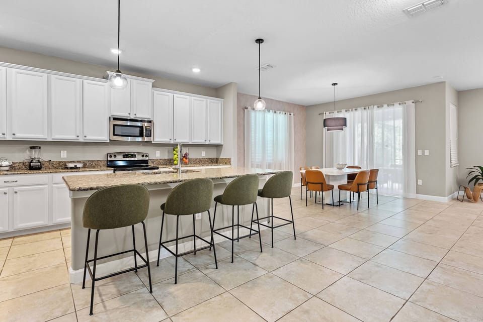 Welcome to this bright and spacious kitchen, where sleek white cabinetry and a stylish granite island create a perfect spot for casual dining.