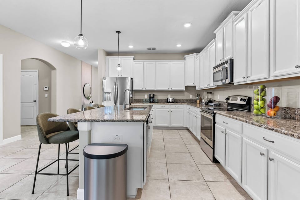 Step into this bright kitchen, featuring sleek white cabinetry and granite countertops that invite culinary creativity. The spacious island provides room for casual dining, while the modern appliances ensure meal prep is a breeze.