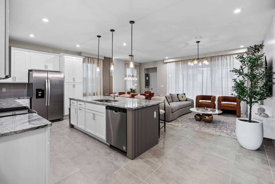 Enjoy a culinary delight in this bright kitchen with elegant granite countertops and a spacious island ideal for gatherings. The cozy living area, featuring stylish armchairs, offers a warm atmosphere perfect for relaxation.
