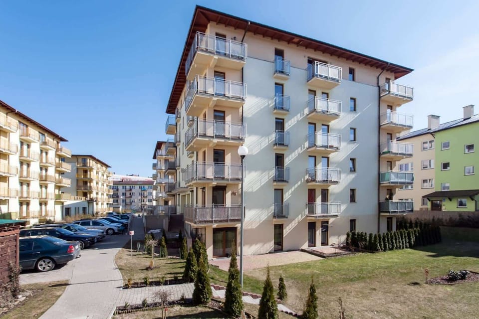 The apartment building with well-maintained greenery and a peaceful neighborhood view.