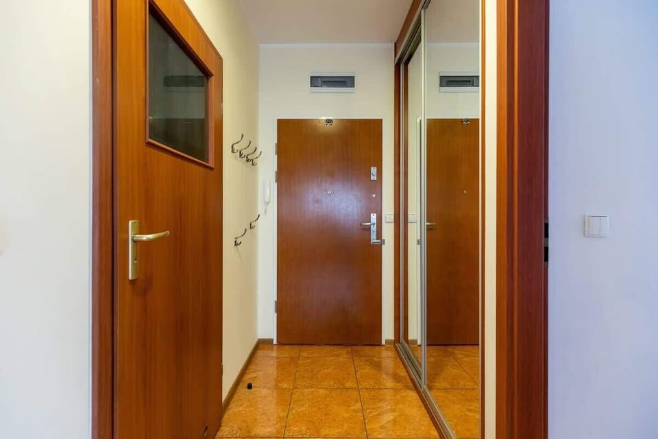 The hallway of the apartment where you can see the wardrobe with mirror on the right and the wall hangings on the right. 