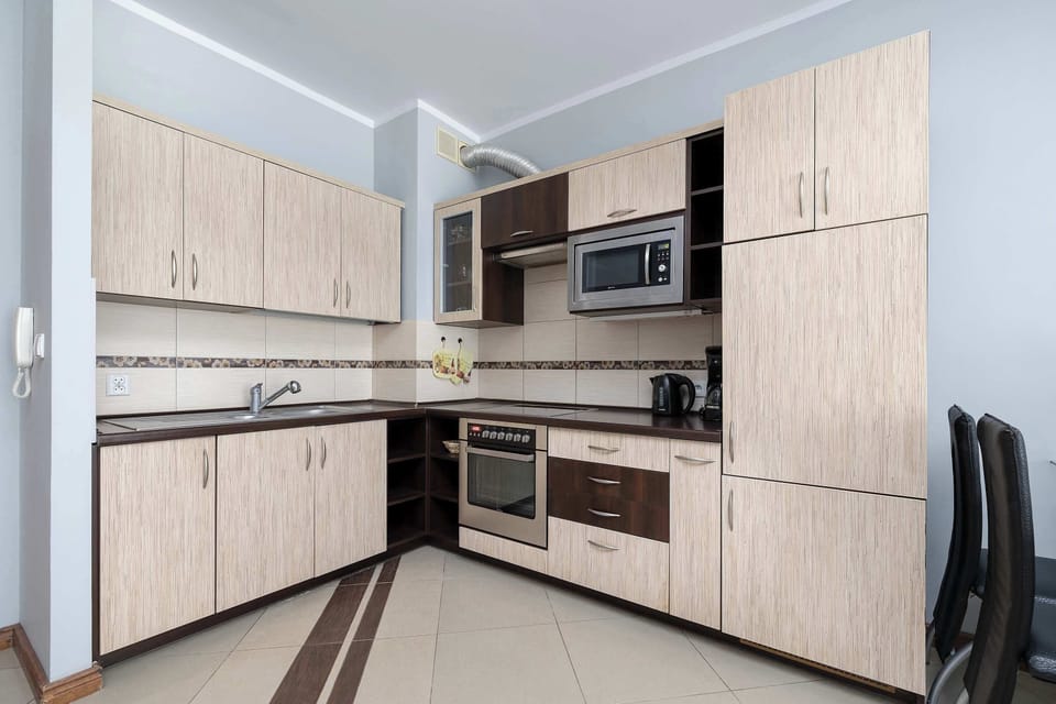 A modern kitchen with light-colored cabinets, an oven, and an induction stove.