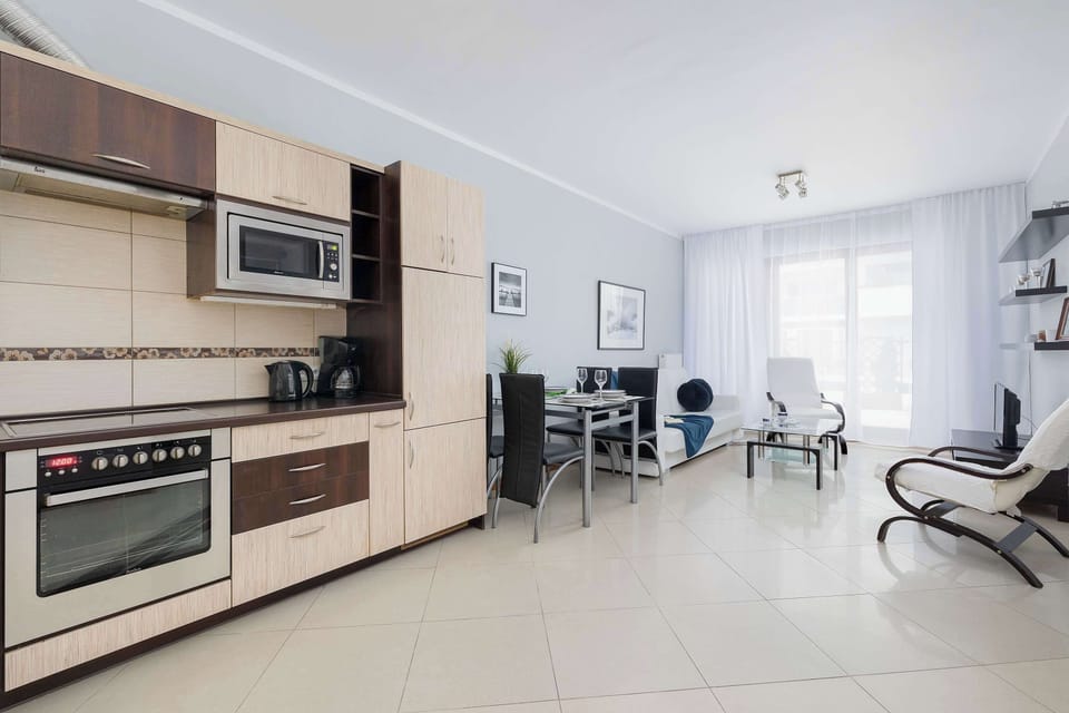 Functional kitchenette with bright furniture and built-in appliances.