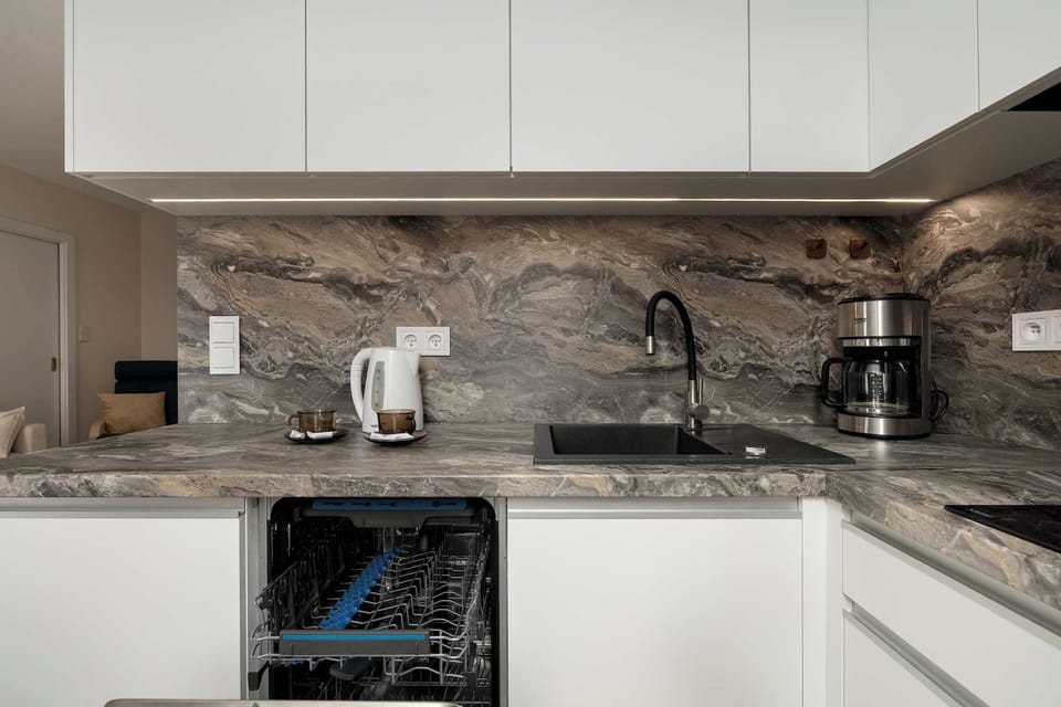 A close-up of a kitchen workspace including a sink, stovetop, and countertop appliances.