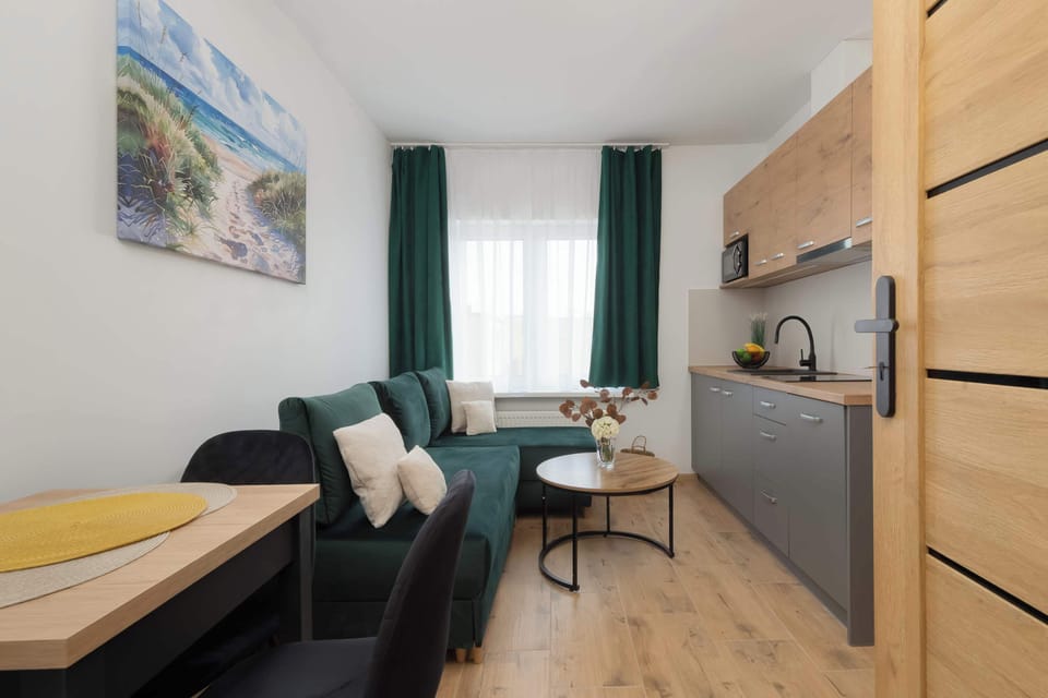 Living area with corner sofa bed, dining area, kitchenette and TV.