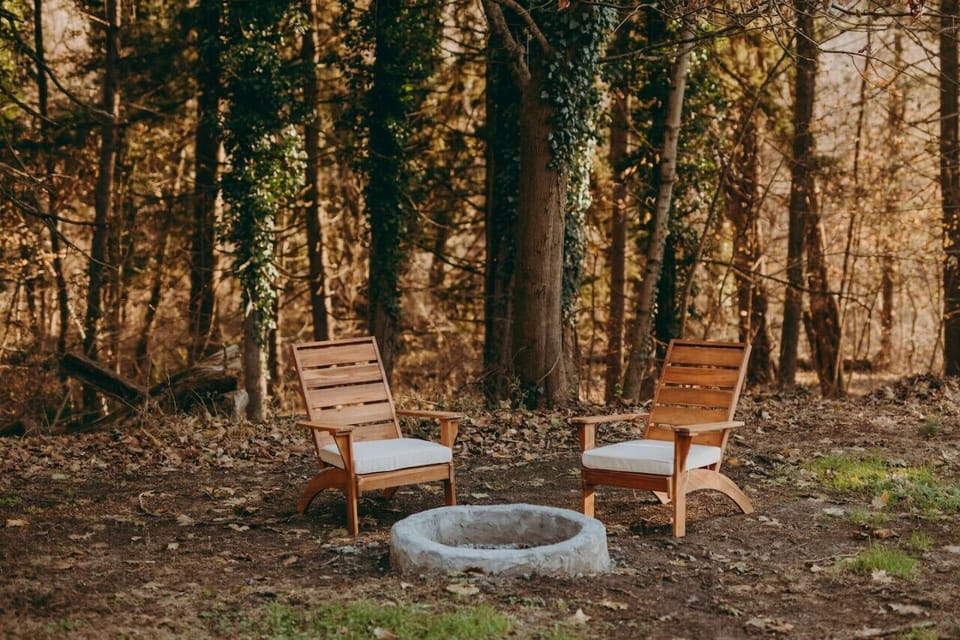 Outdoor area with wooden chairs arranged around a stone fire pit