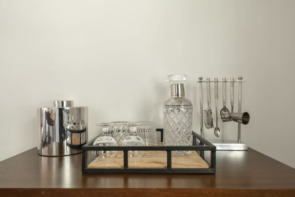 Bar setup with crystal glasses, a decanter, a metal ice container, and various bar tools