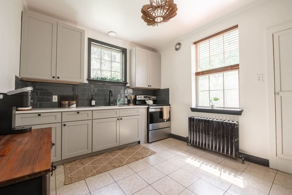 Kitchen with cabinets a window above the sink, a stove, and black tile backsplash
