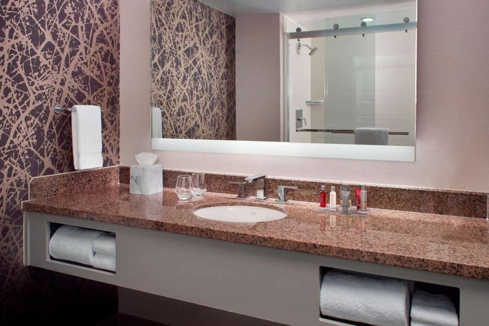 Bathroom with granite counter, wall art, and lighted mirror