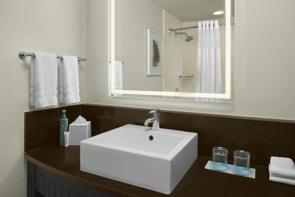 Modern bathroom vanity with vessel sink, LED-backlit mirror &amp; fresh towels