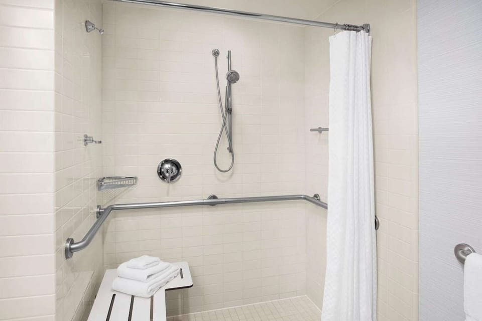 Accessible shower with bench, grab bars, and handheld sprayer