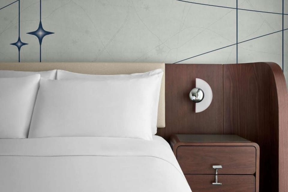Close-up of plush king bed pillows &amp; wood-panel headboard with built-in reading light