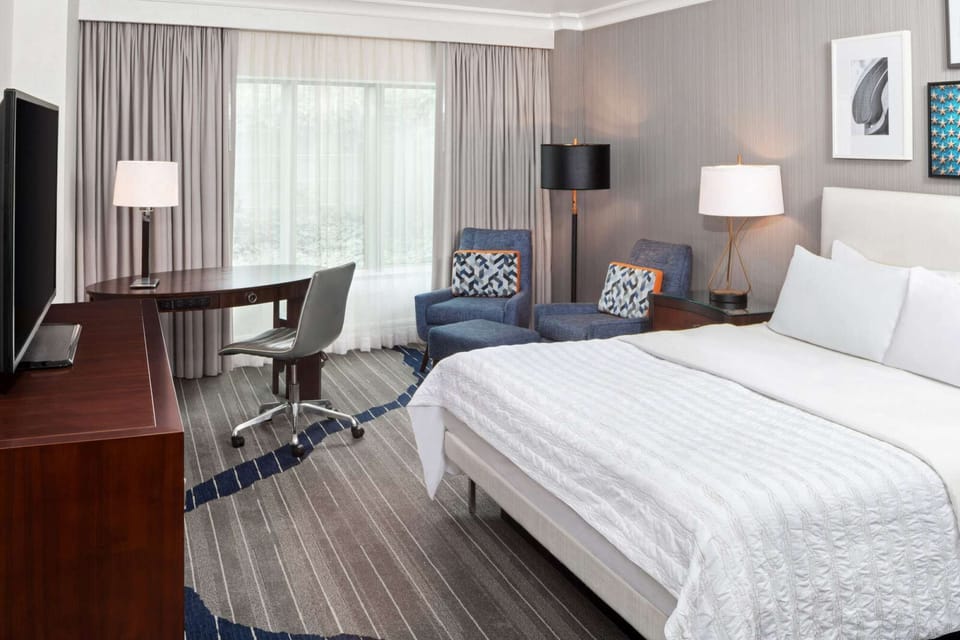 Guest room with king bed, two chairs, and soft natural light