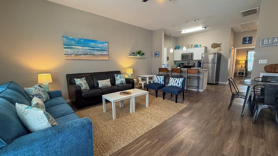 Relax in your coastal-themed living space with comfortable seating and fully equipped kitchen for preparing meals together.