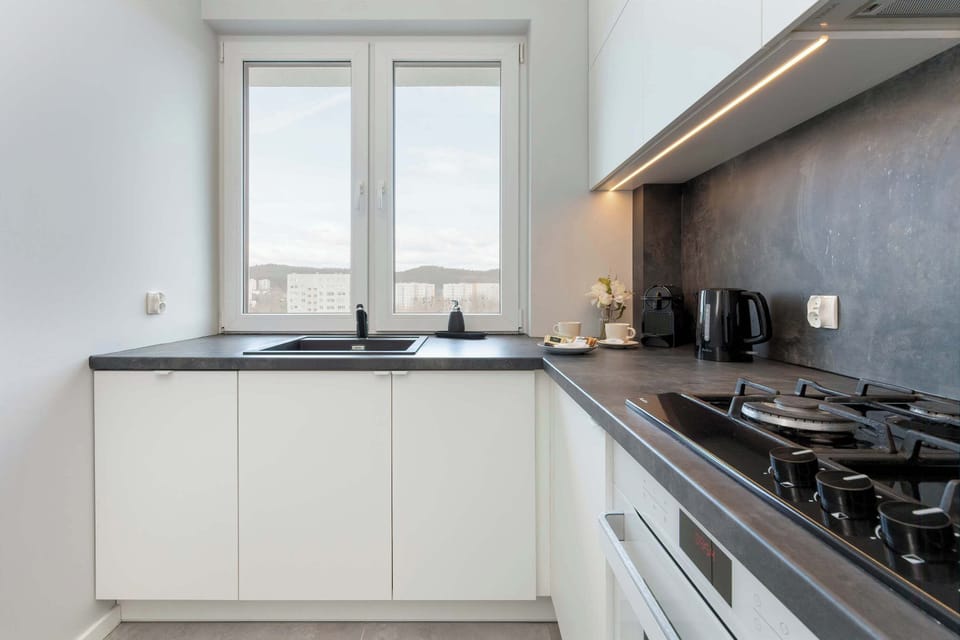 A sleek, fully equipped kitchen with white cabinetry, ample countertop space, and high-quality built-in appliances.