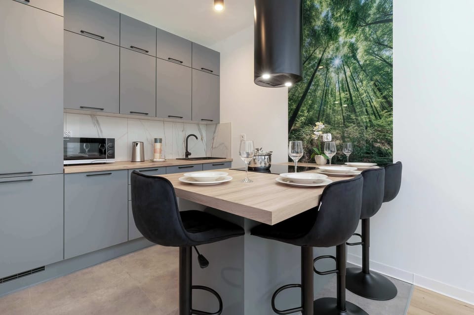 Kitchenette with grey modern furniture and high-quality appliances. The countertop provides a comfortable place to eat meals together.