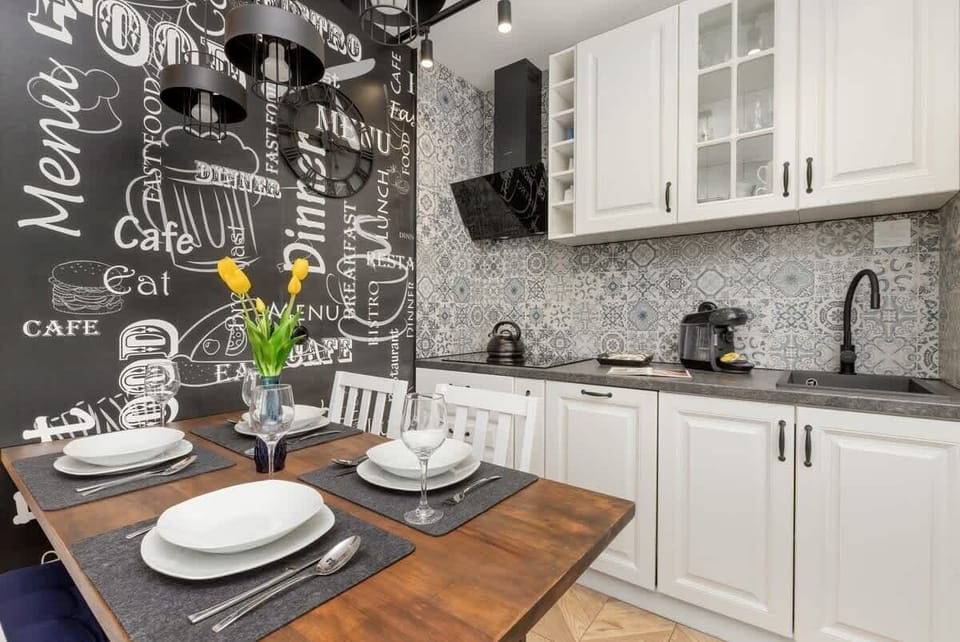 A stylish kitchenette with modern cabinetry, patterned backsplash, and sleek appliances, perfect for compact yet functional cooking.