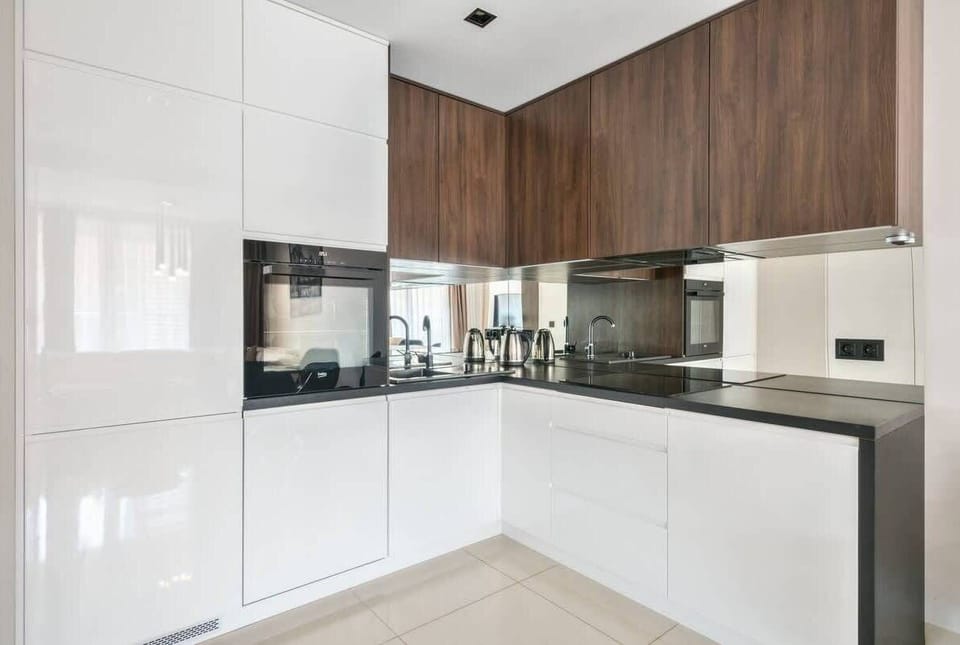A sleek, modern kitchen with white cabinetry, integrated appliances, and a tiled floor. The space feels bright and functional.

