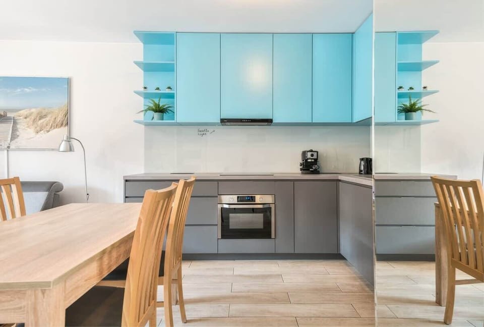 Practical kitchen with elegant light grey cabinets and wooden dining table with chairs.
