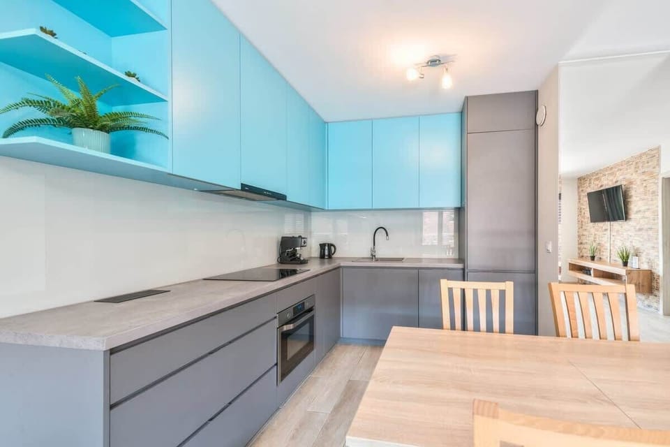 Practical kitchen with elegant light grey cabinets and wooden dining table with chairs.
