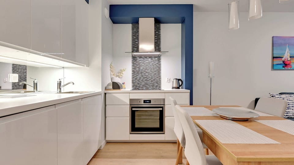 An open-plan studio featuring a small dining area next to a living room with a sofa and artwork.