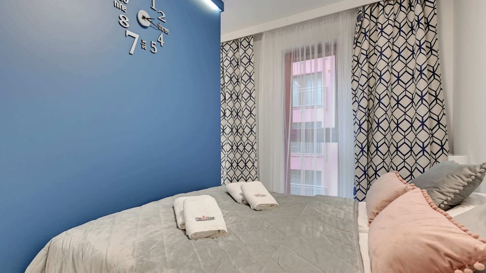 A cozy sleeping corner with a double bed, cushions, and light curtains.