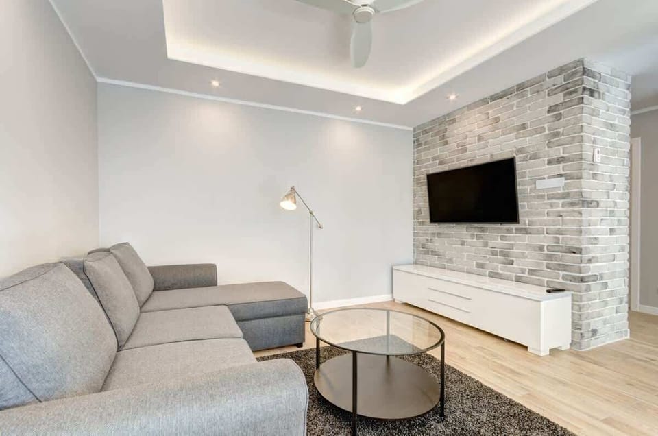A modern living room in light, neutral colors with an accent of gray brick on the wall, creates an elegant and cozy space, ideal for relaxation and leisure.