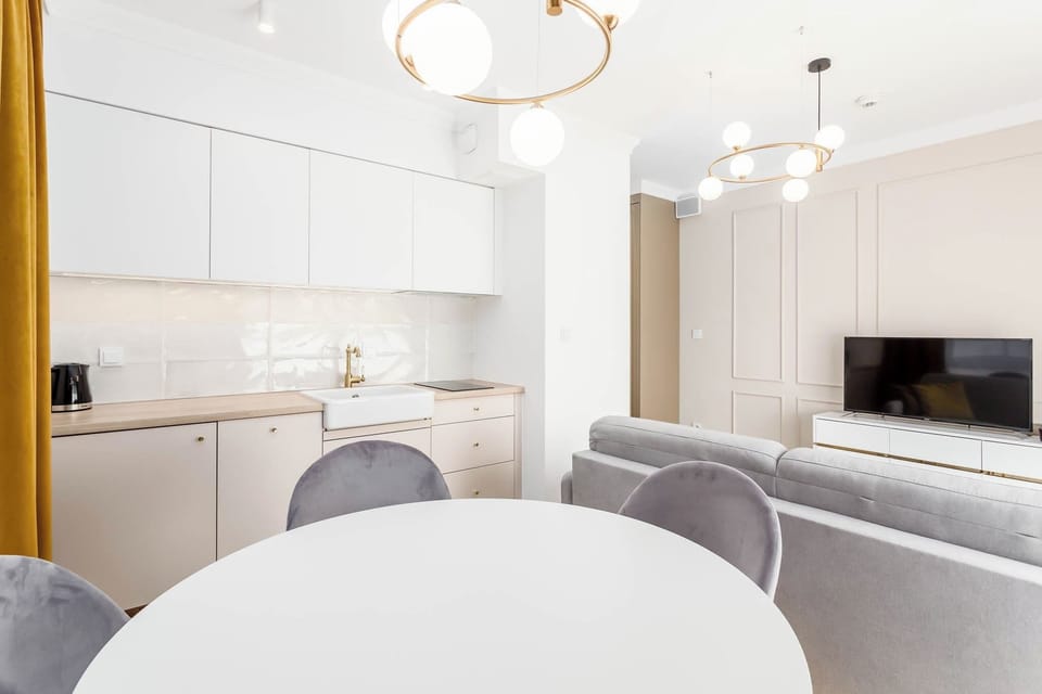 A combined area with a round dining table and a sofa facing the TV. The layout is modern and practical.