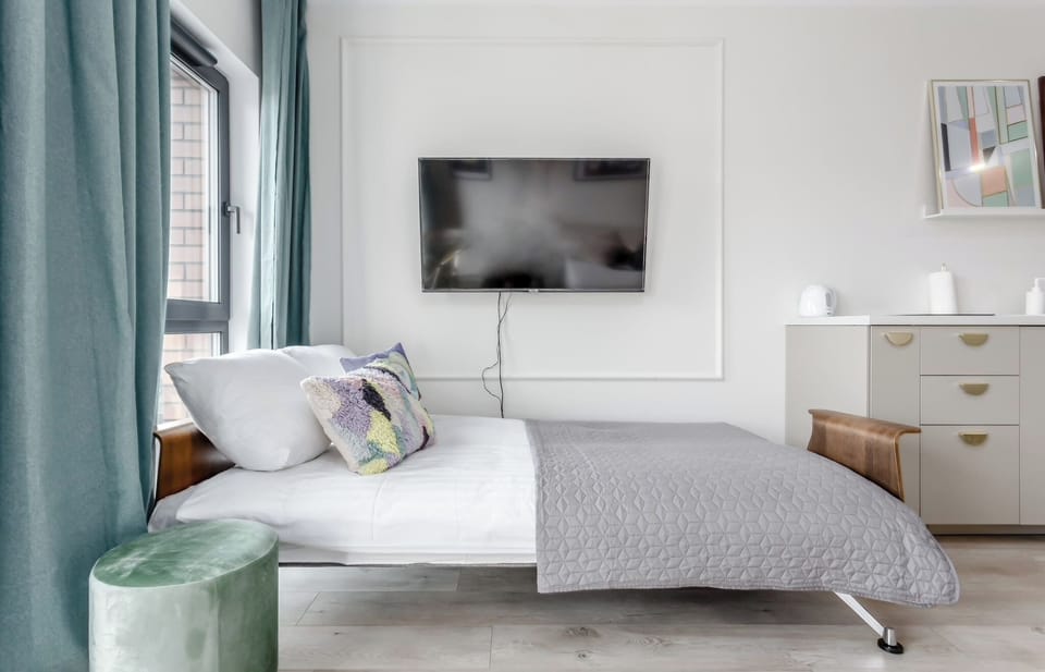 Another perspective of the bedroom with the bed in focus and curtains framing the view. A desk and chair are visible near the window.