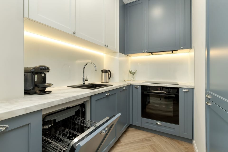 A compact and modern kitchenette with built-in appliances, perfect for preparing quick meals. Subtle lighting and sleek cabinetry add a touch of elegance.