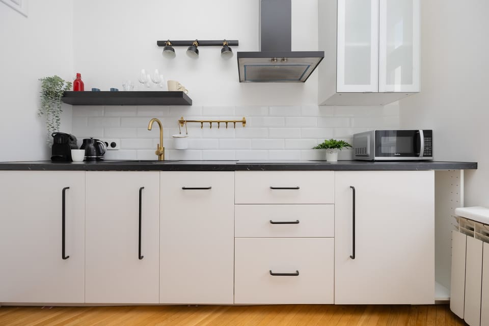 A compact kitchen with white cabinets, black countertops, and essential appliances, blending into the living space.