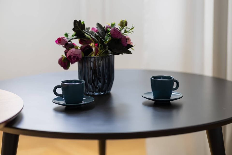 A close-up of a round black dining table with two cups and a vase of fresh flowers, creating a welcoming ambiance.