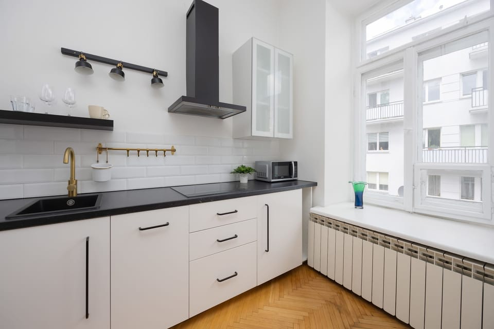 A compact kitchen with white cabinets, black countertops, and essential appliances, blending into the living space.