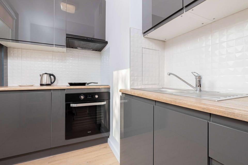 A closer look at a modern kitchen with sleek grey cabinetry. Visible appliances include an oven and a cooktop, with ample counter space.