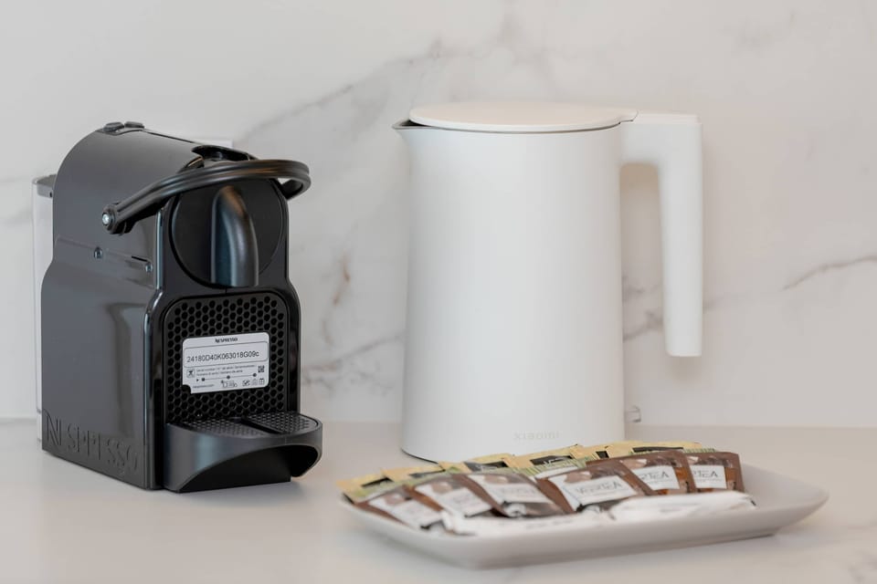 Stylish setup with a coffee machine, electric kettle, mugs, and cookies.