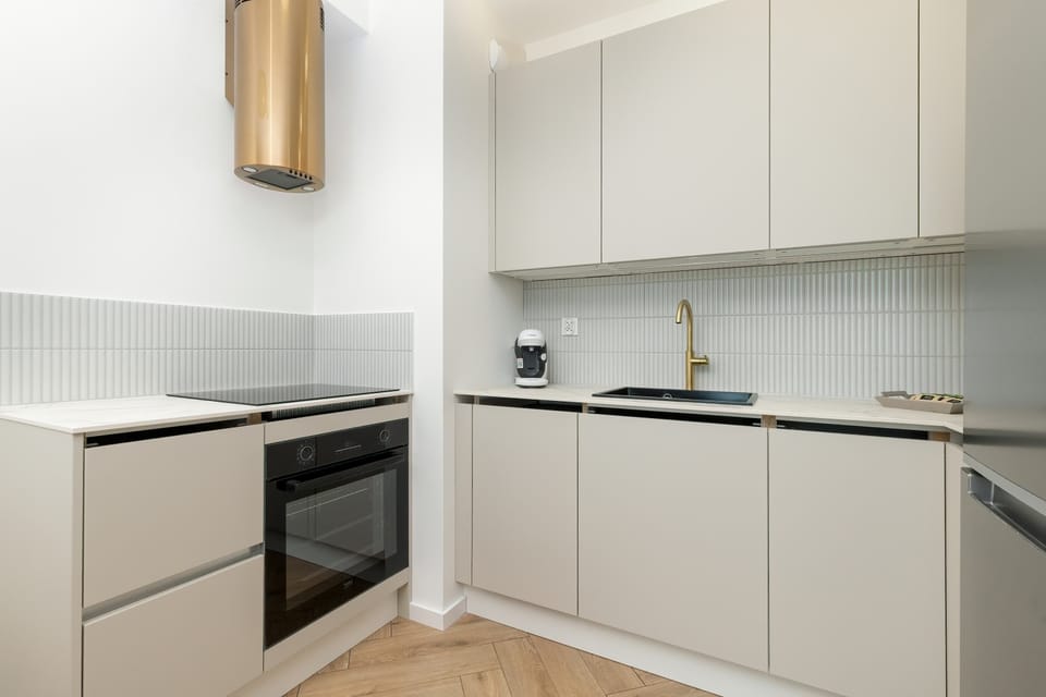 A stylish, minimalist kitchen with modern appliances, bright cabinets, and a functional layout, perfect for preparing meals in a homey setting.